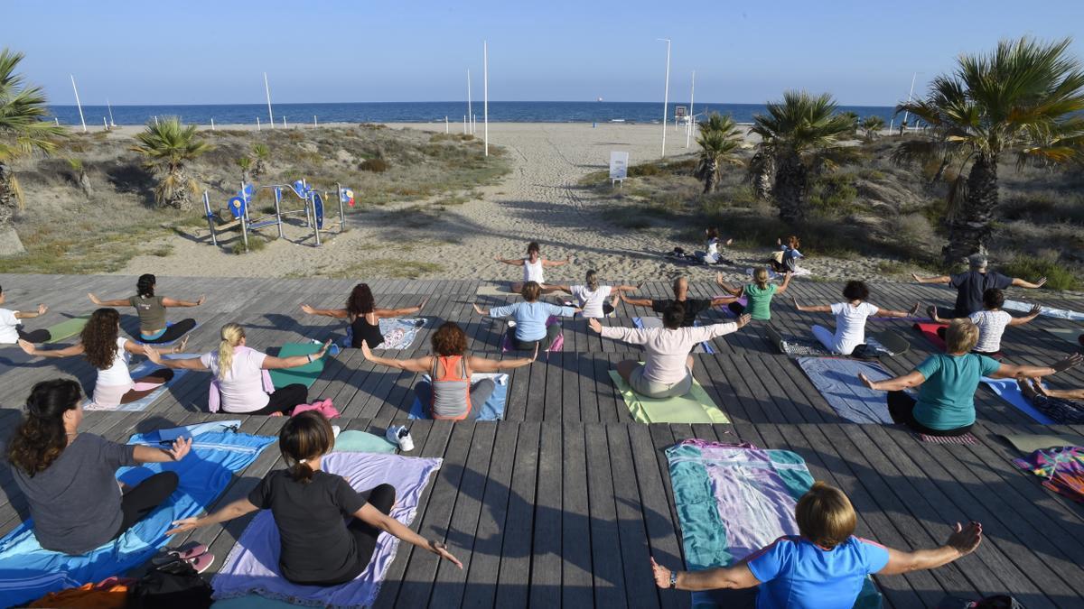 Un grup de persones fa una activitat esportiva dirigida en una platja de Castelló