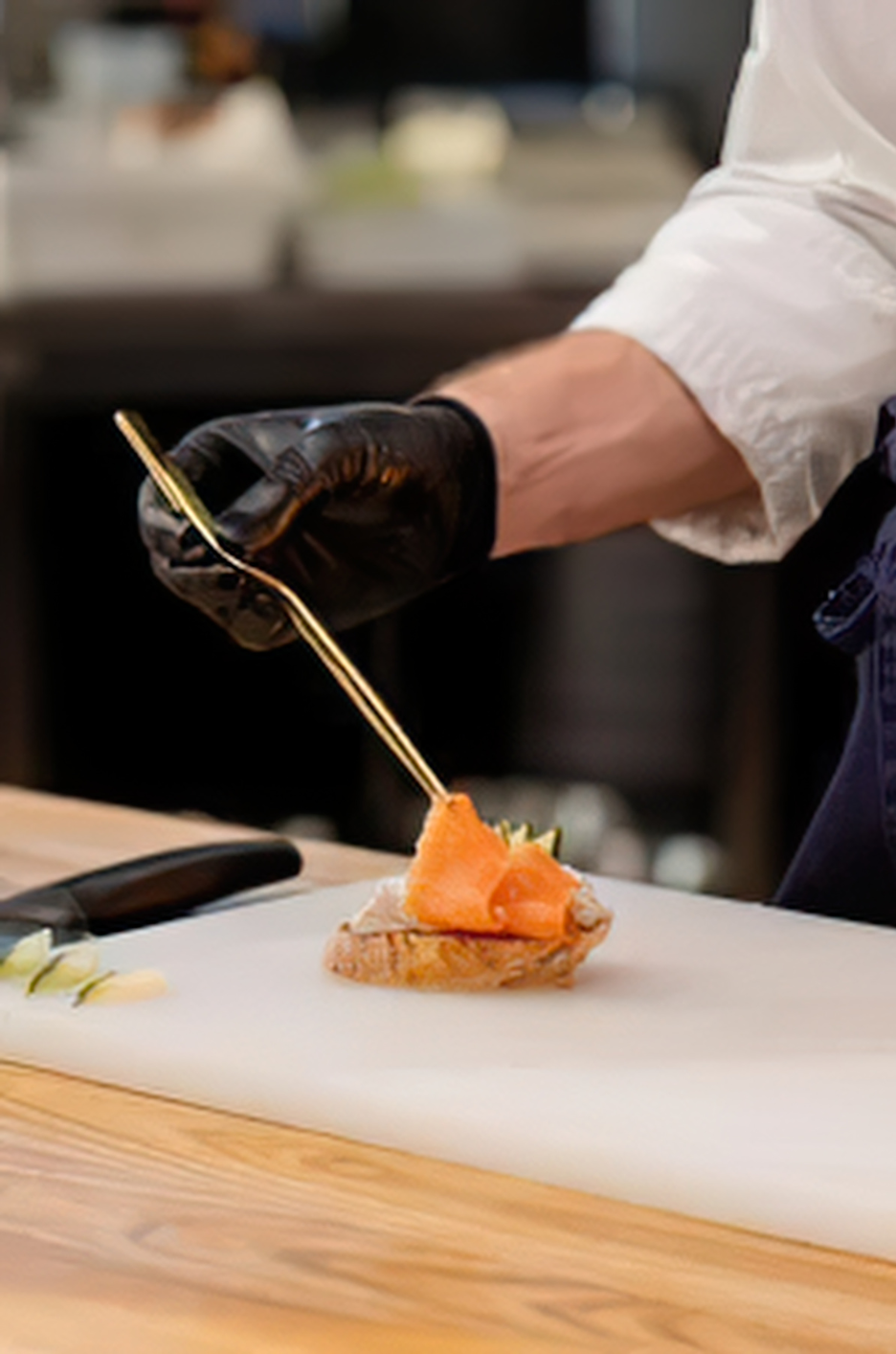 Un chef poniendo una loncha del salmón ahumado en un plato